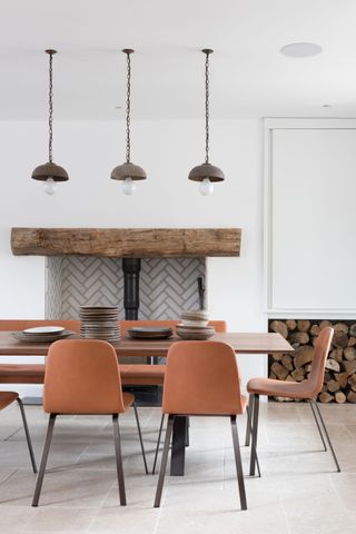 Orange clay coloured dining chairs, long wooden dining table with black legs, rustic hanging lights