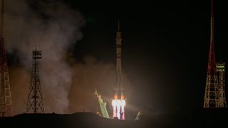 a rocket launches at night, leaving a streak of fire behind it