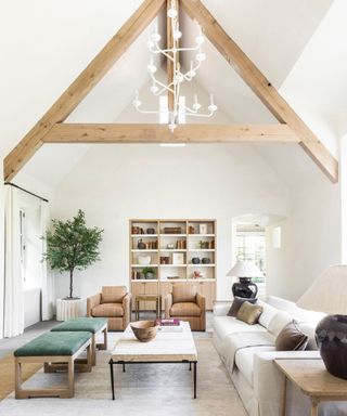 light and airy living room with white walls, sloped ceiling with exposed wooden beams, neutral sofa and calming decor