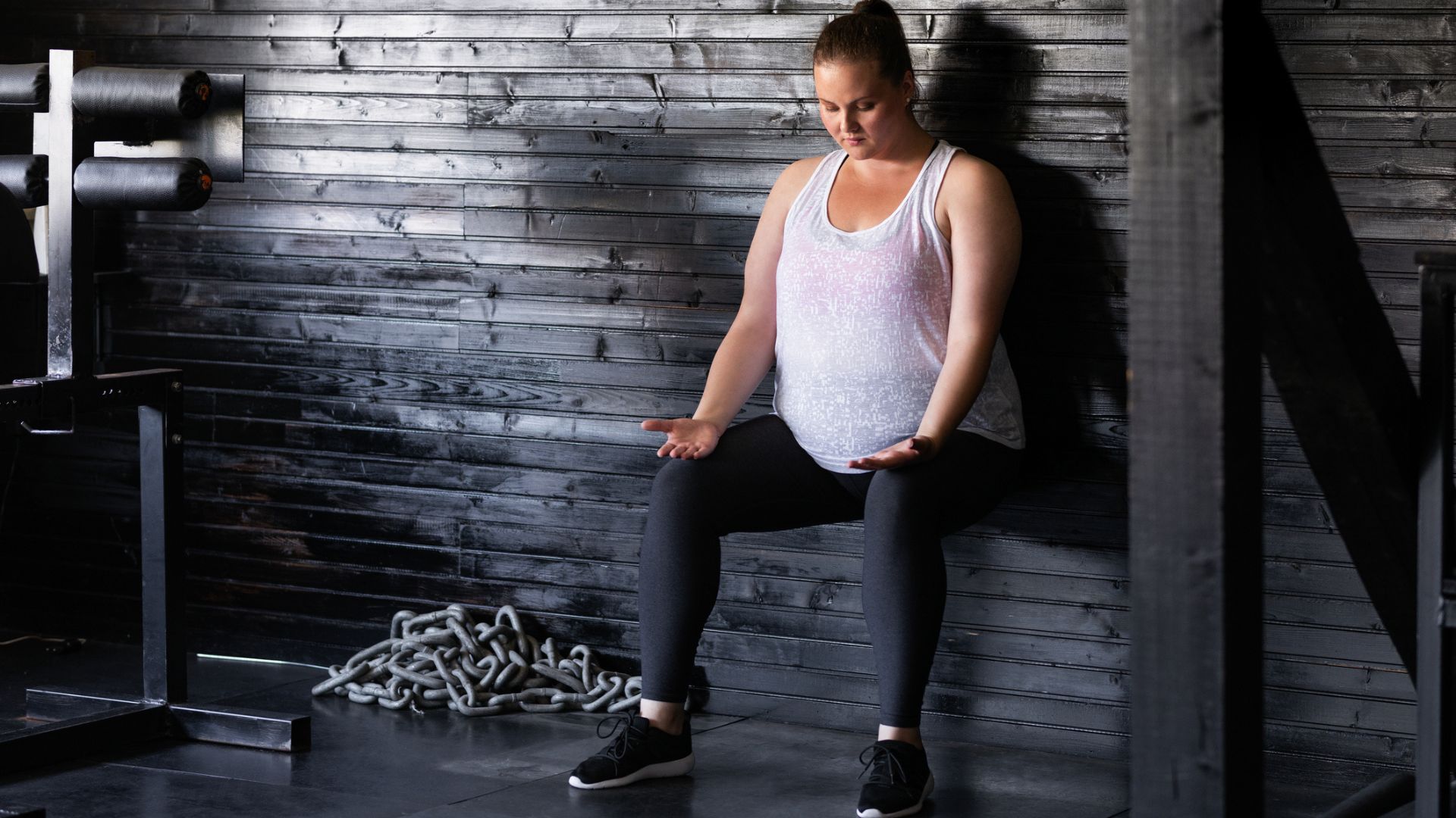 A woman performs a wall squat indoors