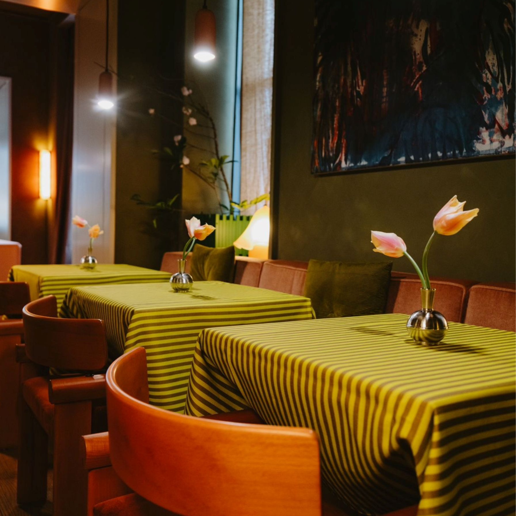 row of tables with striped green and brown tablecloths and wooden chairs