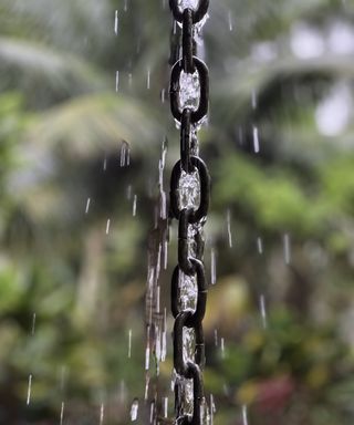 Black rain chain with water running down it