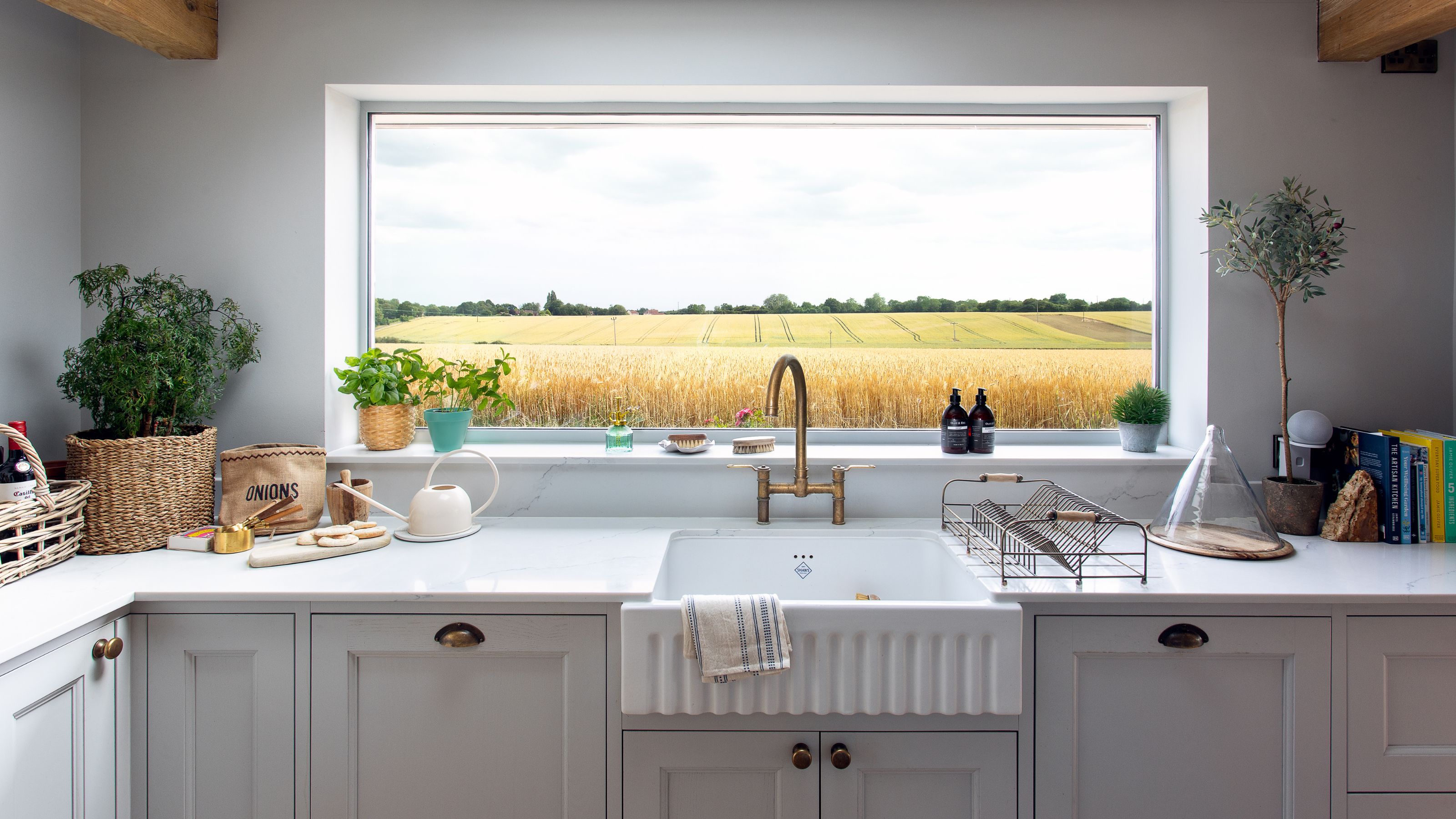 Kitchen sink and worktops with a large window in front, showing far-reaching views of fields