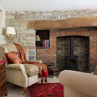 stone wall room fire place with red brick wall cream colour sofa with cushion