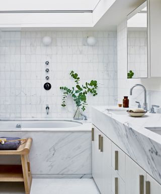 marble and tile bathroom with double vanity and bath tub