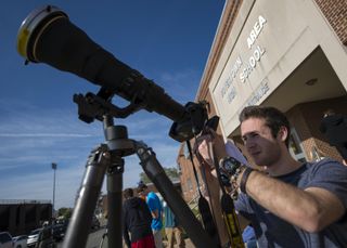 A student uses his smartphone and a photographers lens with a solar filter to capture a photo of the planet Mercury transiting the sun on May 9, 2016.