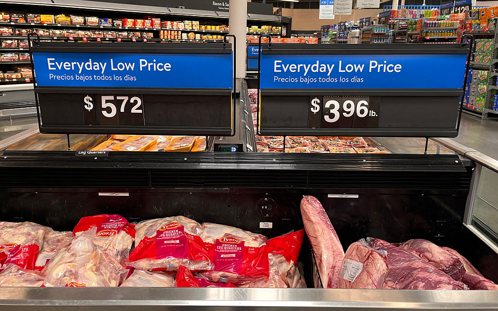 Walmart price signs above a freezer filled with various cuts of meat.