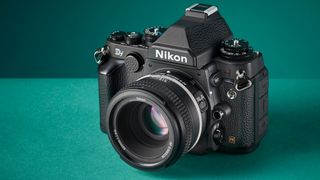 Studio image of a Nikon Df camera with 50mm lens on a turquoise background