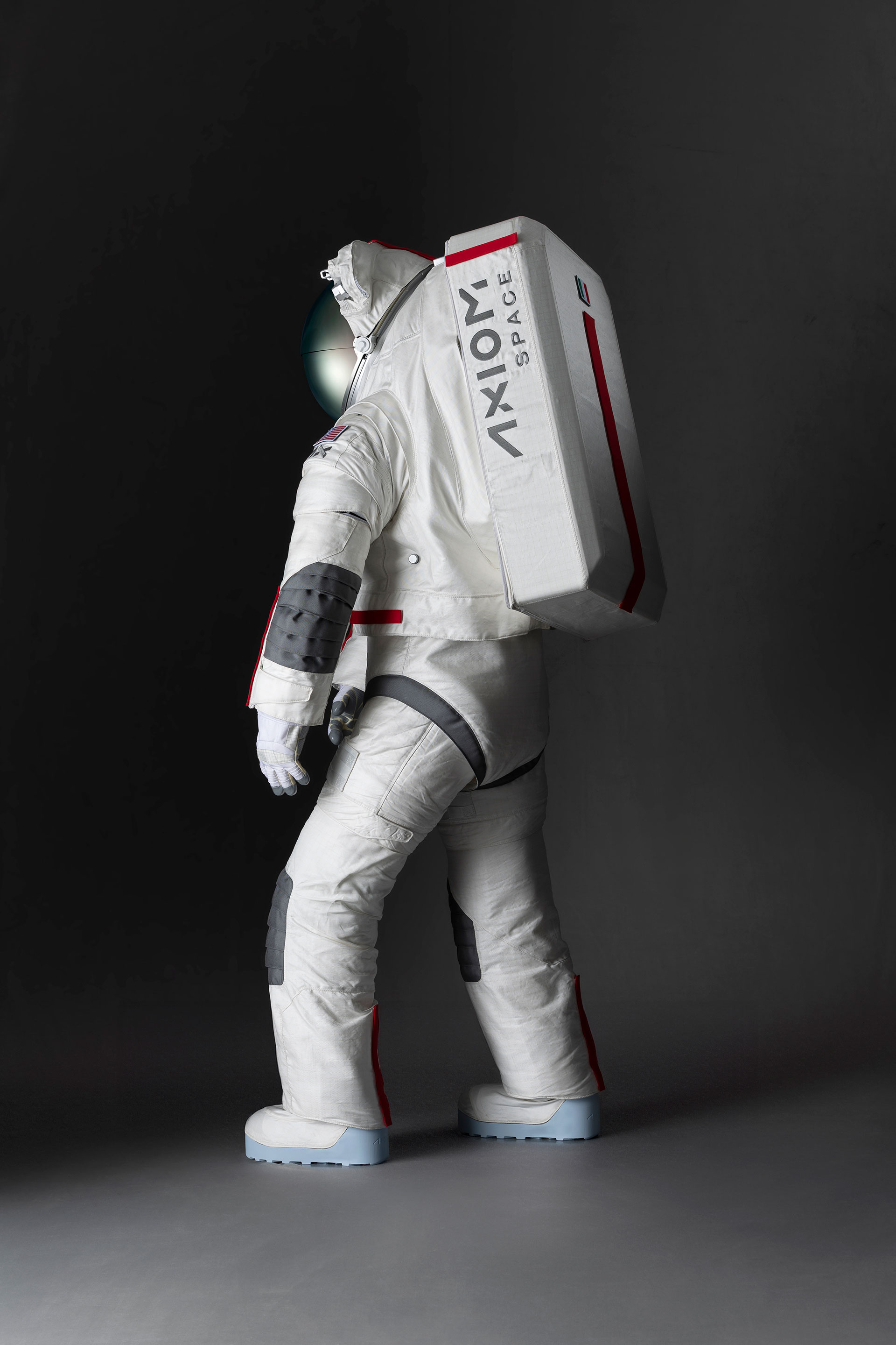 side view of a white spacesuit standing against a gray background