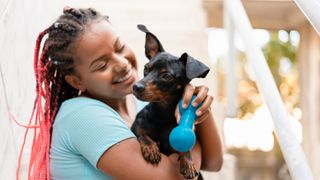 Woman cuddling puppy and holding toy