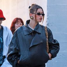 Hailey Bieber leaving church in a moto jacket 80s earrings tiny sunglasses and leggings