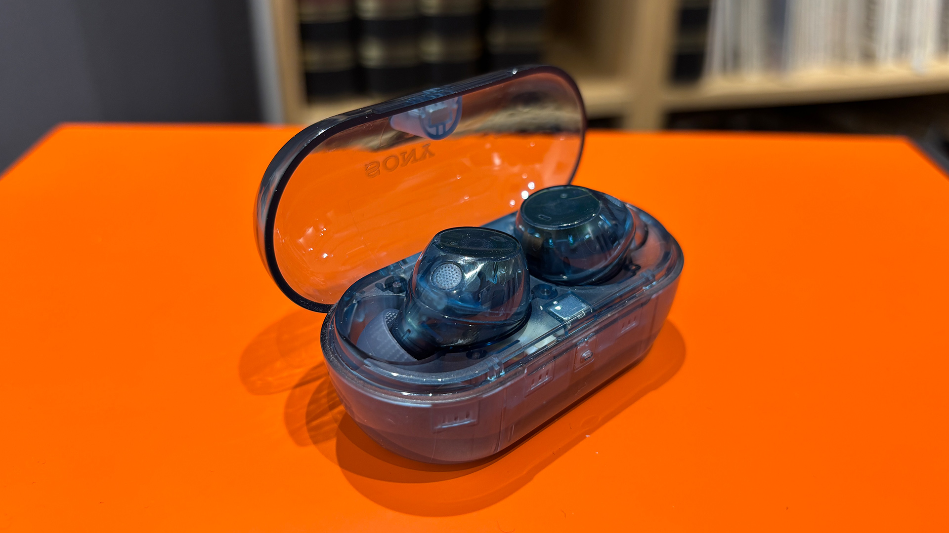 Sony WF-C710N in-ear headphones in case on top of orange table