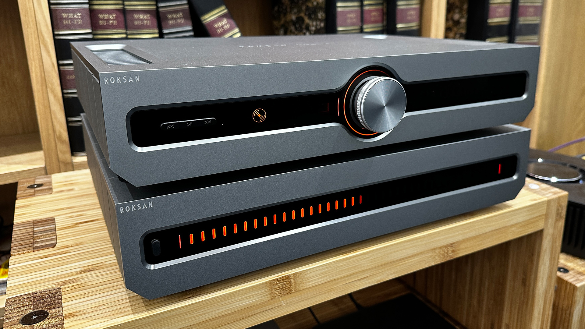 Roksan Caspian 4G Streaming Pre-Amplifier/Caspian 4G Power Amplifier on wooden hi-fi rack in front of bookcase
