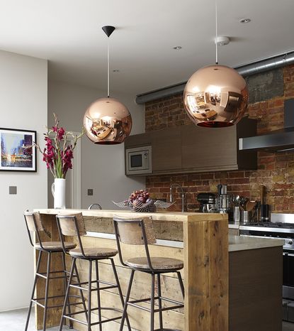 kitchen area wiith brick wall and wood counter with chair and kitchen units