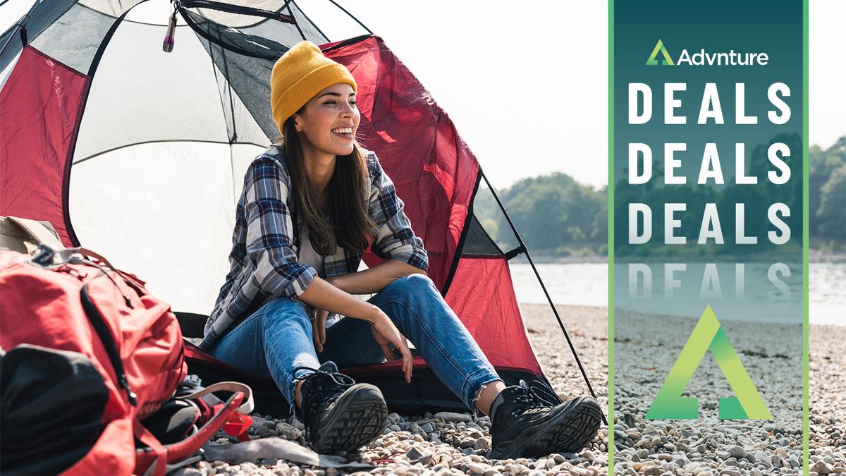 Happy woman sitting in tent beside lake