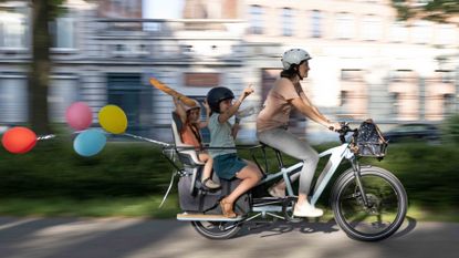 Image shows woman riding the Elops R500 e cargo bike with two child passengers