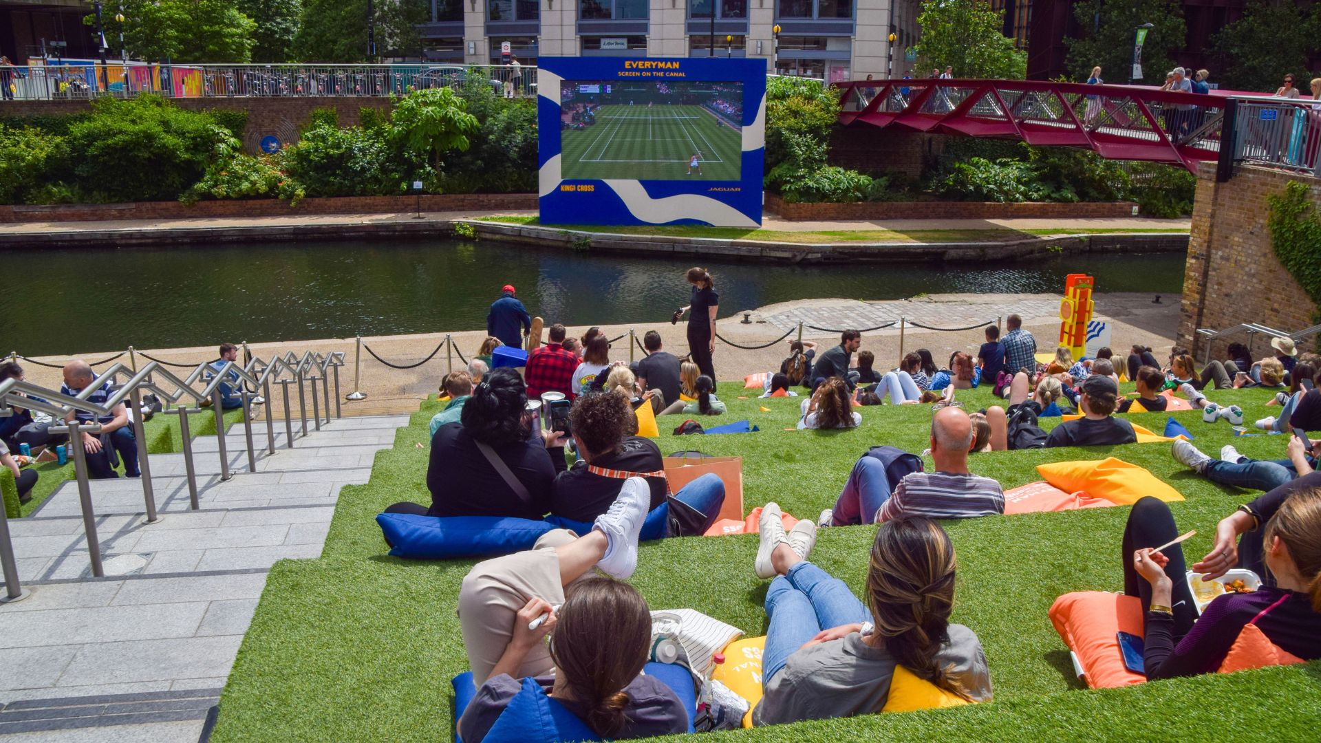 LONDON, UNITED KINGDOM - 2023/07/03: Crowds watch a Wimbledon tennis match on a large outdoor screen next to Regent's Canal in King's Cross as this year's championship begins