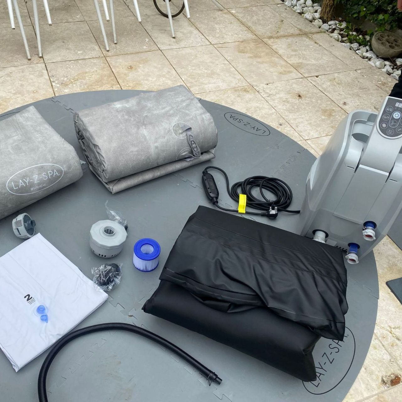 Lay-Z-Spa Zurich EnergySense box contents on the floor with the lining and exterior rolled up next to the grey pump