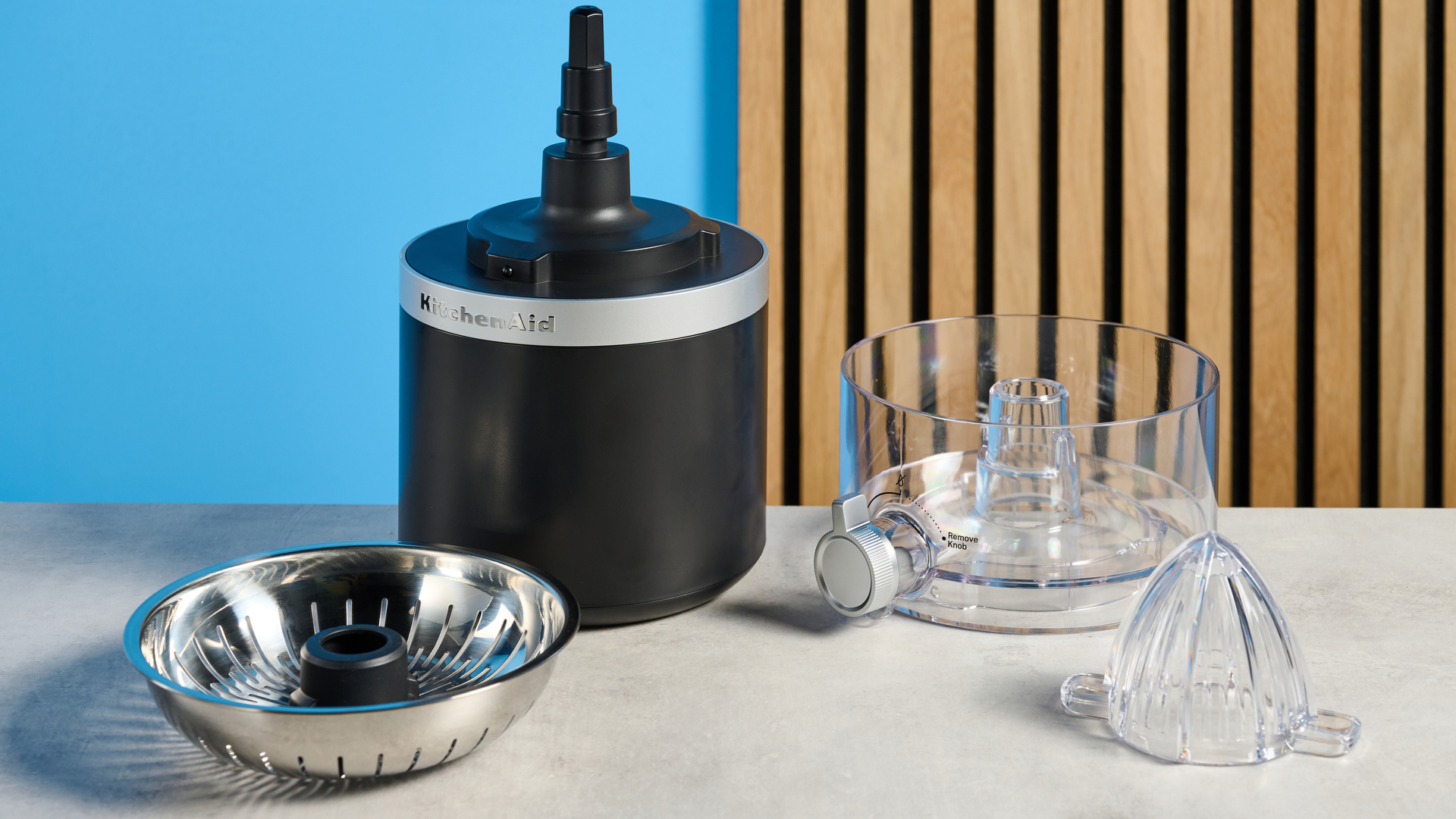KitchenAid Go Cordless Citrus Juicer in matte black photographed in front of a blue background.