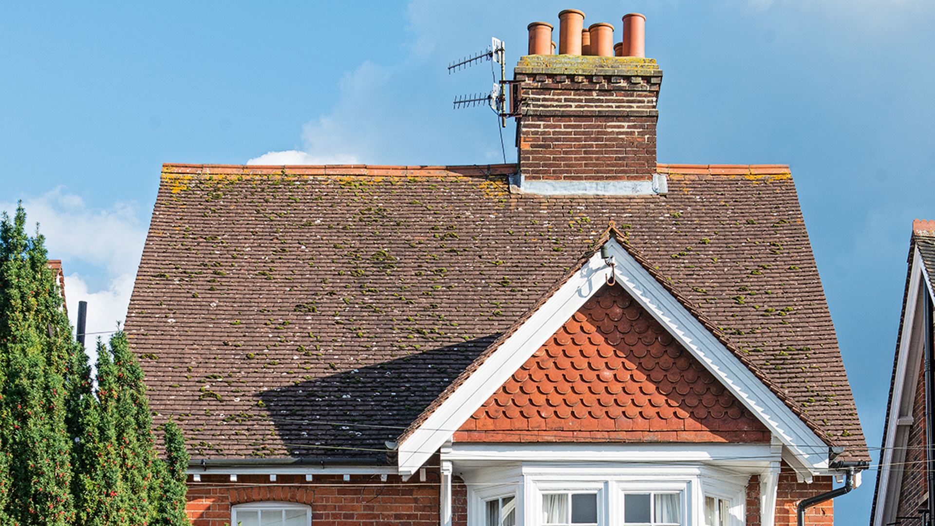 Close up of a house exterior showing roof tiles and a chimney