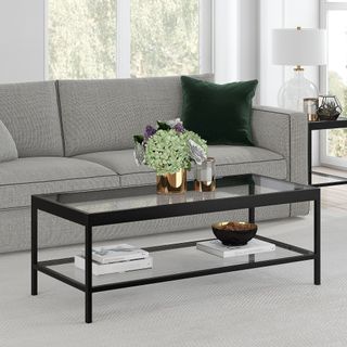 A glass rectangular coffee table with two tiers and a black frame