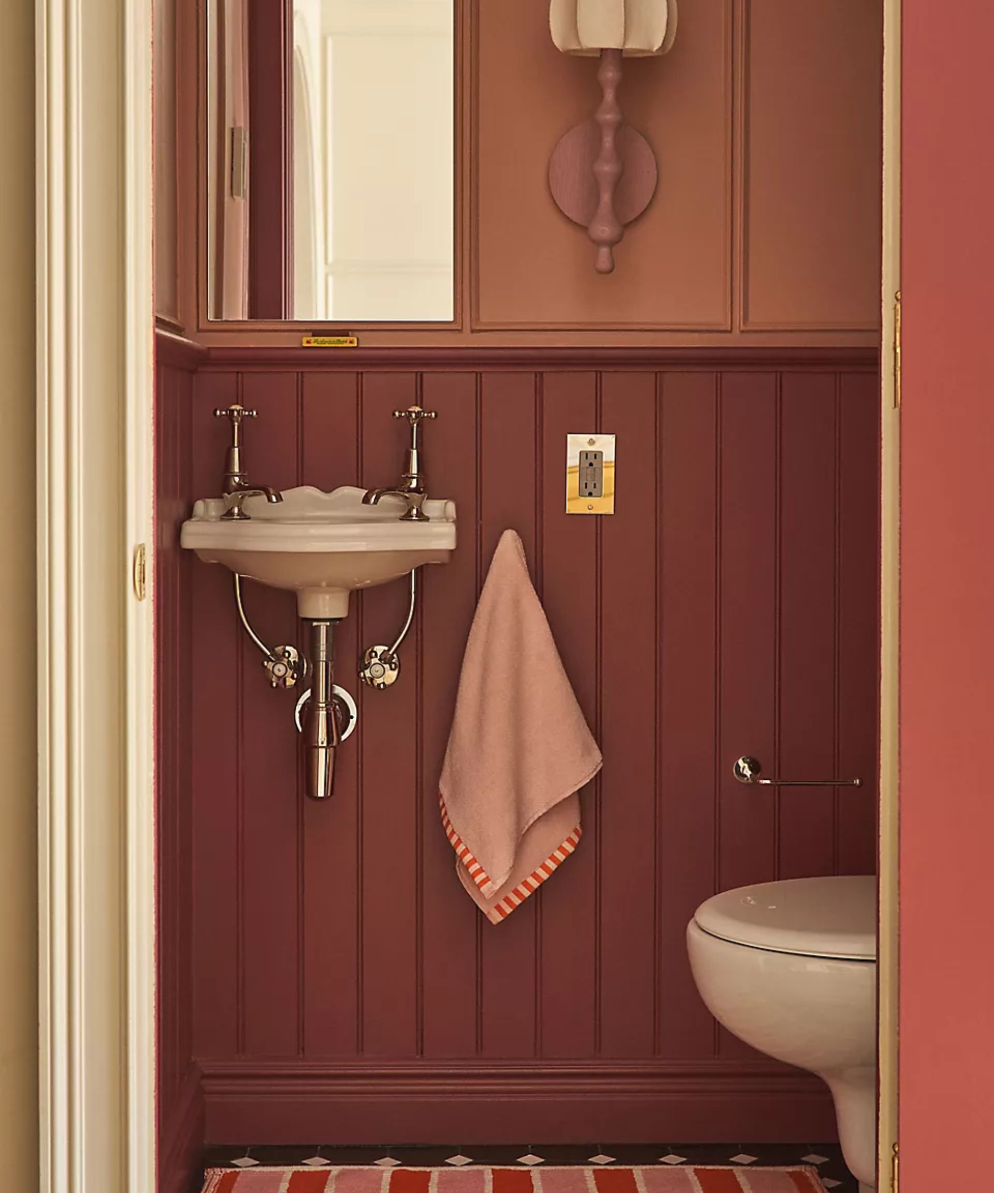 pink panelled powder room small bathroom with a striped bath mat and hand towel