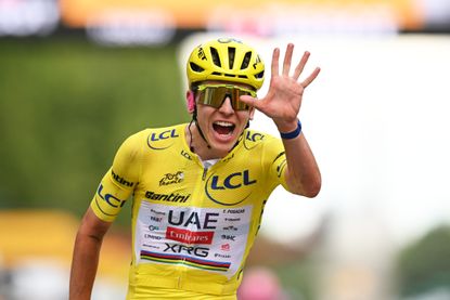 Tadej Pogačar signalling five with his hand celebrating at the Tour de France