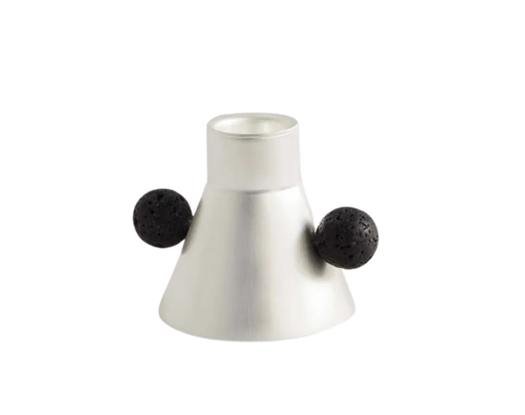 A silver candle holder with two black pons pons on each side.