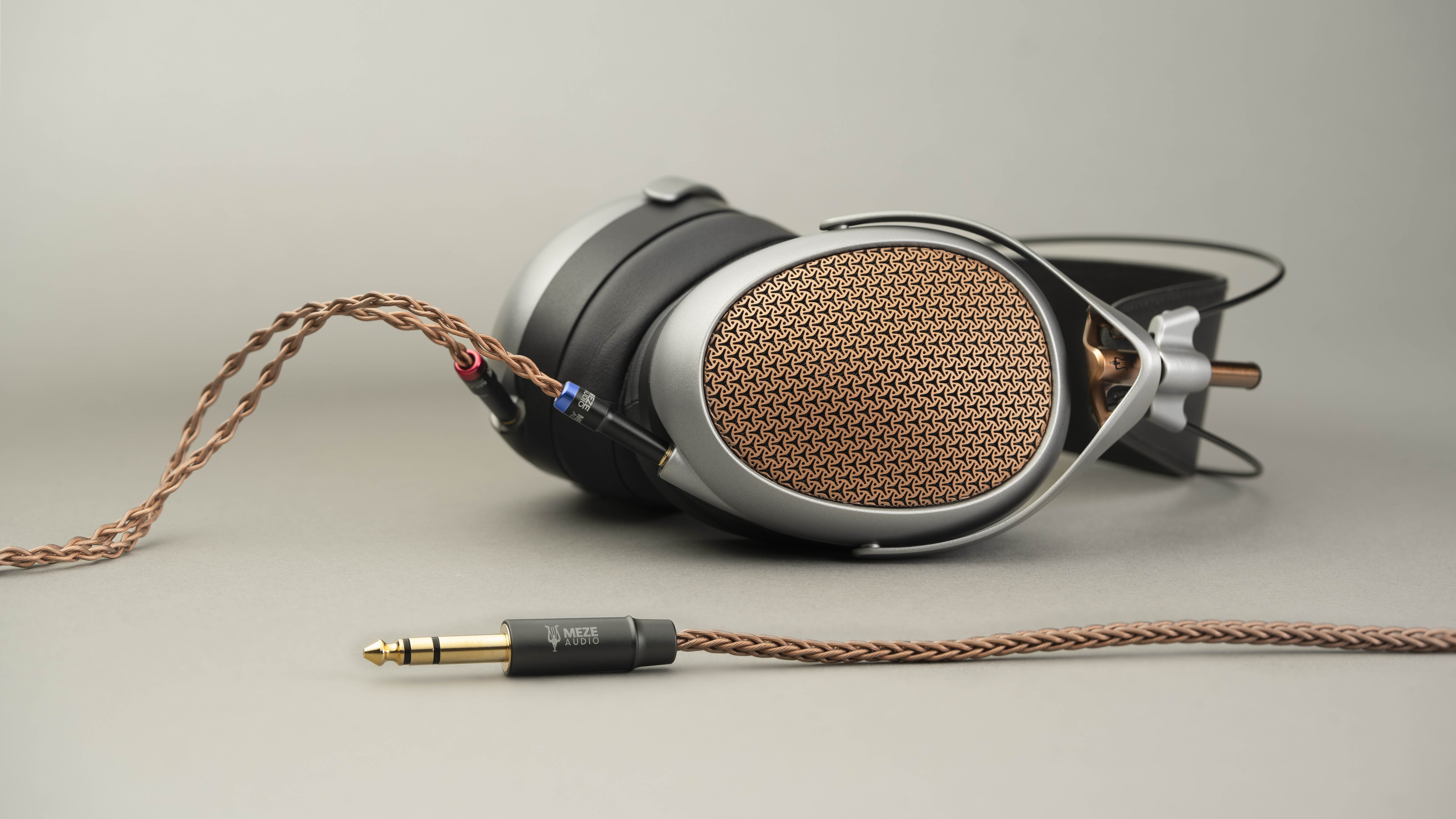 Premium over-ear headphones with copper, gray and black detailing against beige background.