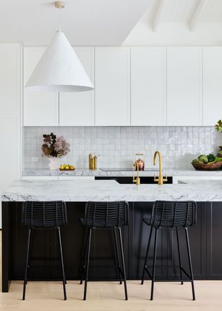 A sleek black and white kitchen with a large pendant light above a marble kitchen island.