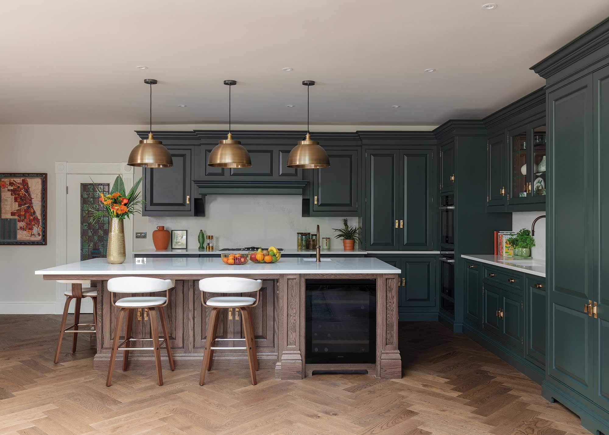 green kitchen with wooden kitchen island and brass cabinet hardware