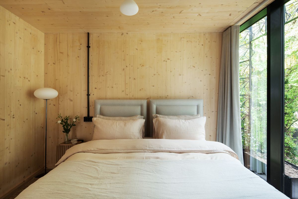 A bedroom with a double bed and plywood walls