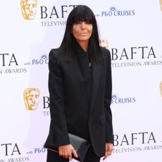Claudia Winkleman wears black capri pants, white heels and a black blazer on the BAFTA red carpet.