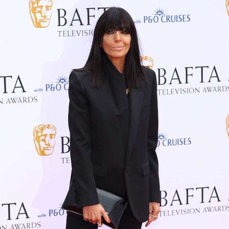 Claudia Winkleman wears black capri pants, white heels and a black blazer on the BAFTA red carpet.