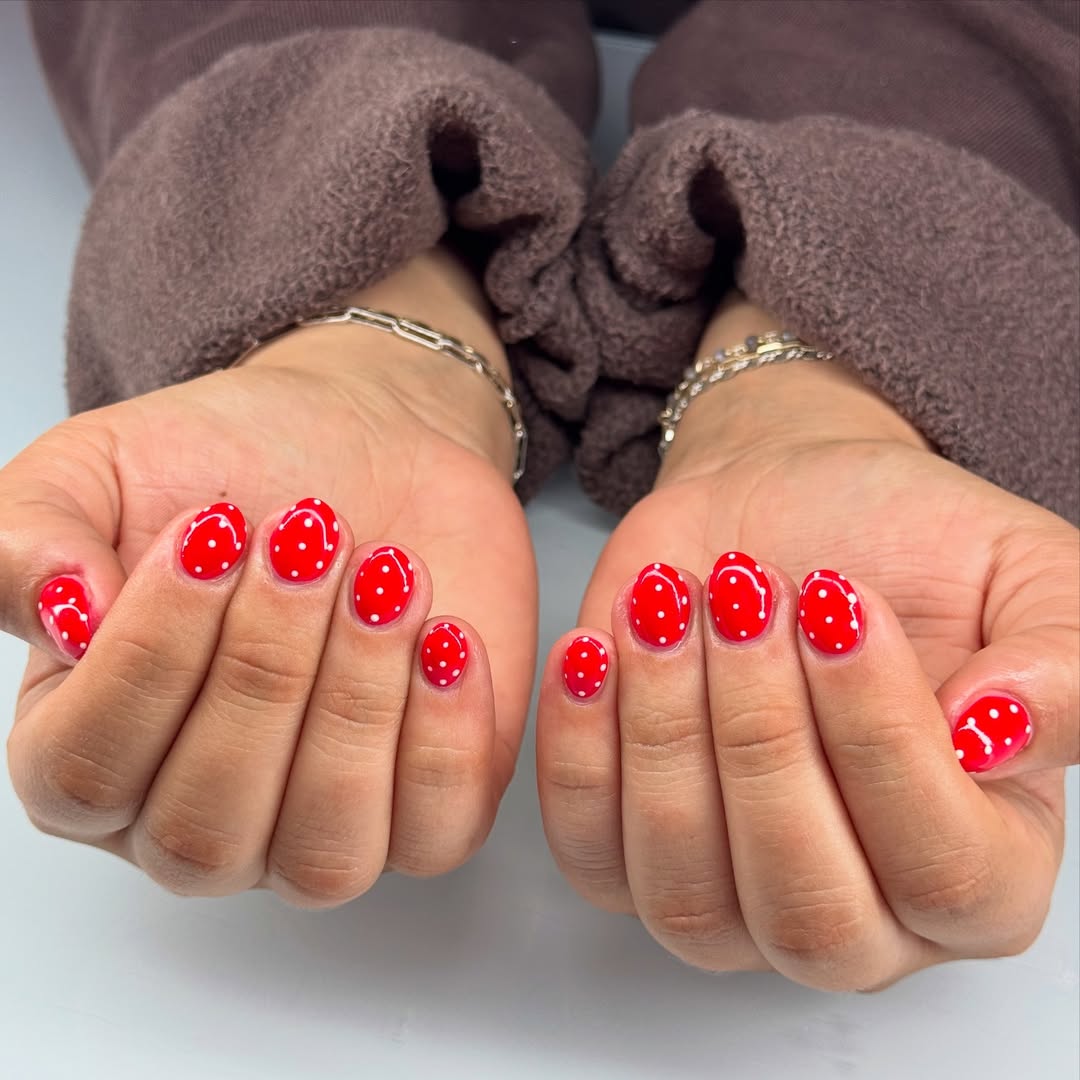 a bright red manicure with white polka dots
