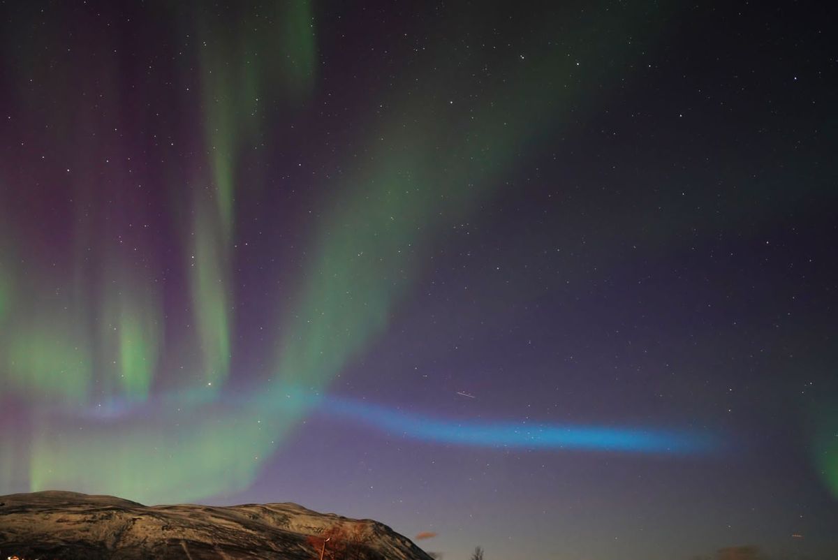 blue ribbon of light appearing over Abisko National Park, Sweden.