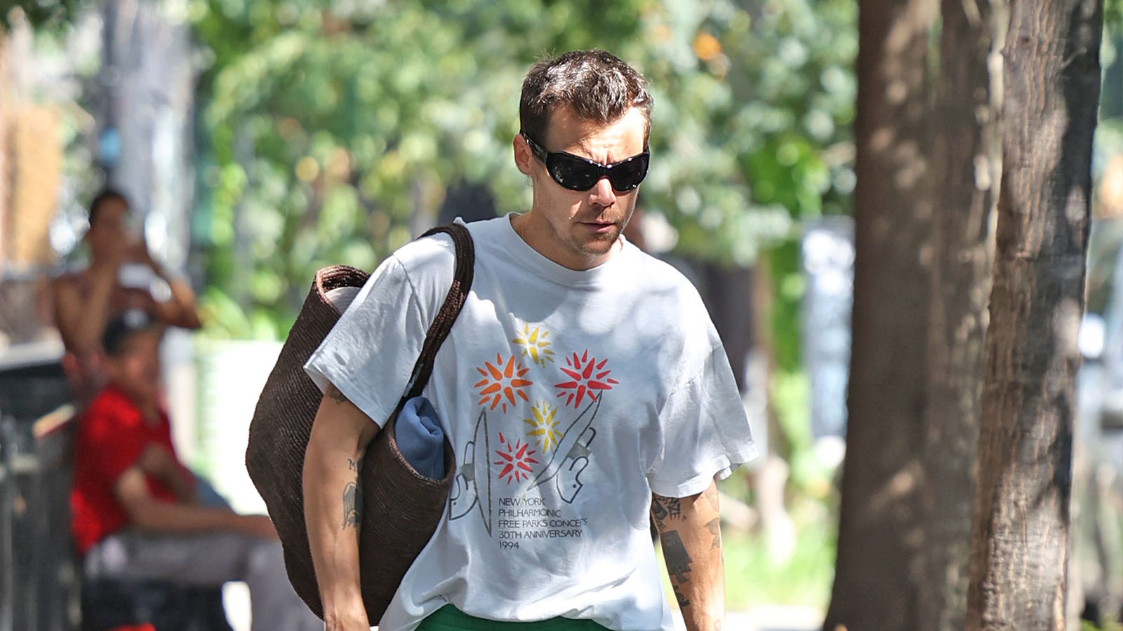 Harry Styles wearing a graphic t-shirt, green shorts, and brown boat shoes