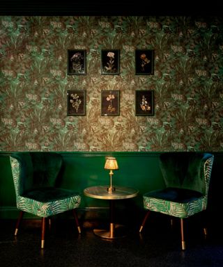 Bar area decorated in geeps green and patterned wallpaper to create a moody scheme