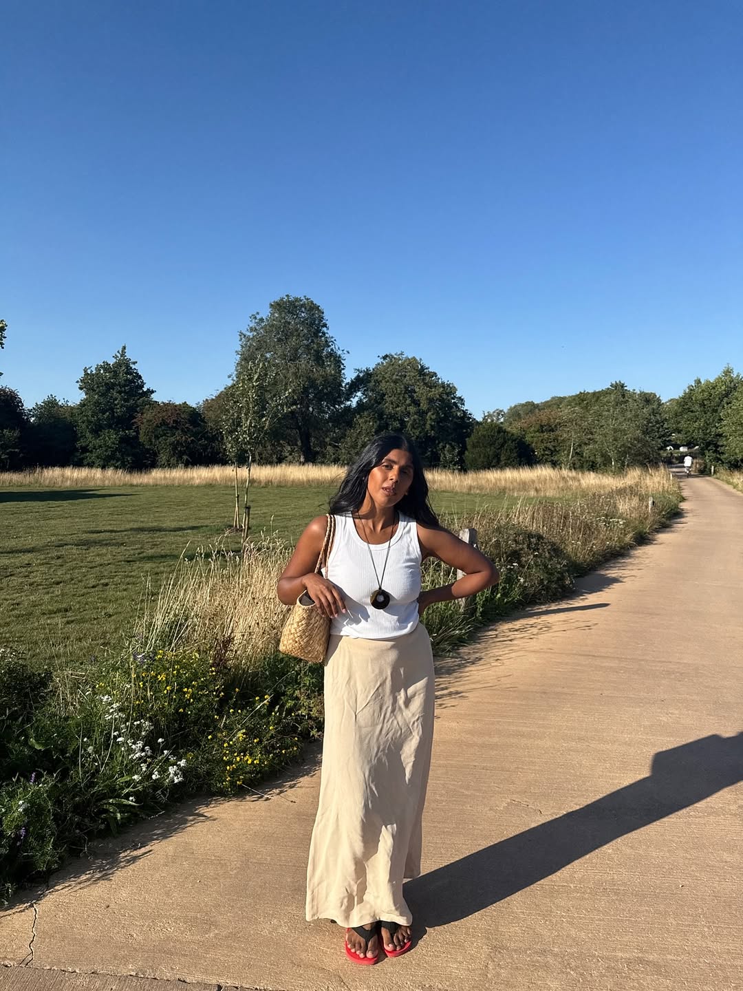 @monikh wears white vest top pendant necklace and skirt