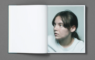 Open book with photo of head shot of teenage girl looking to the left on the right page.