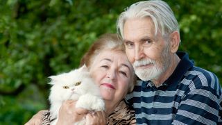 Two pensioners holding white Persian cat