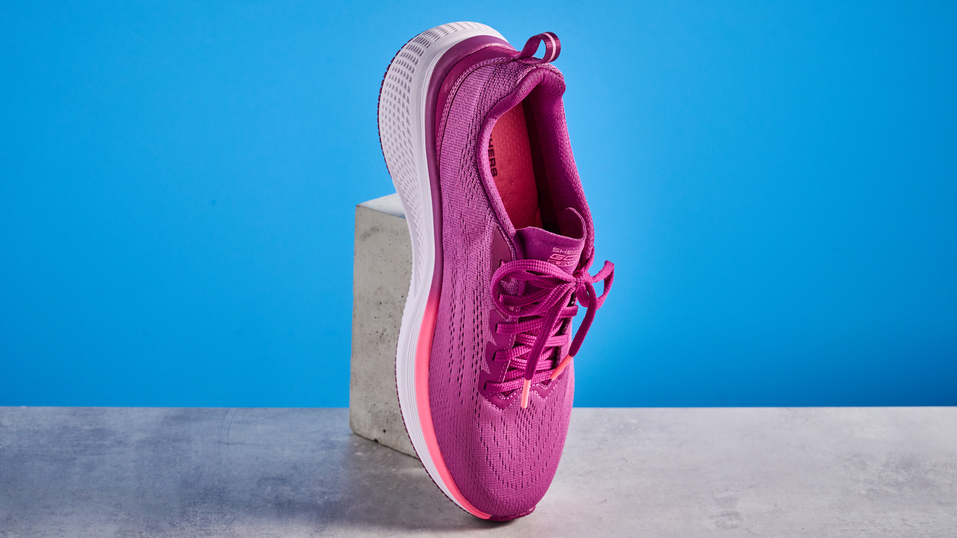 the skechers go run elevate 2.0 running shoes in the women's style, in fuchsia pink, photographed against a blue background