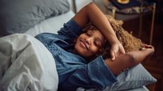 A woman lying in bed looking happy and relaxed after sleeping well