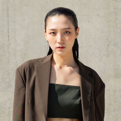 korean model with glowing skin wearing a brown blazer