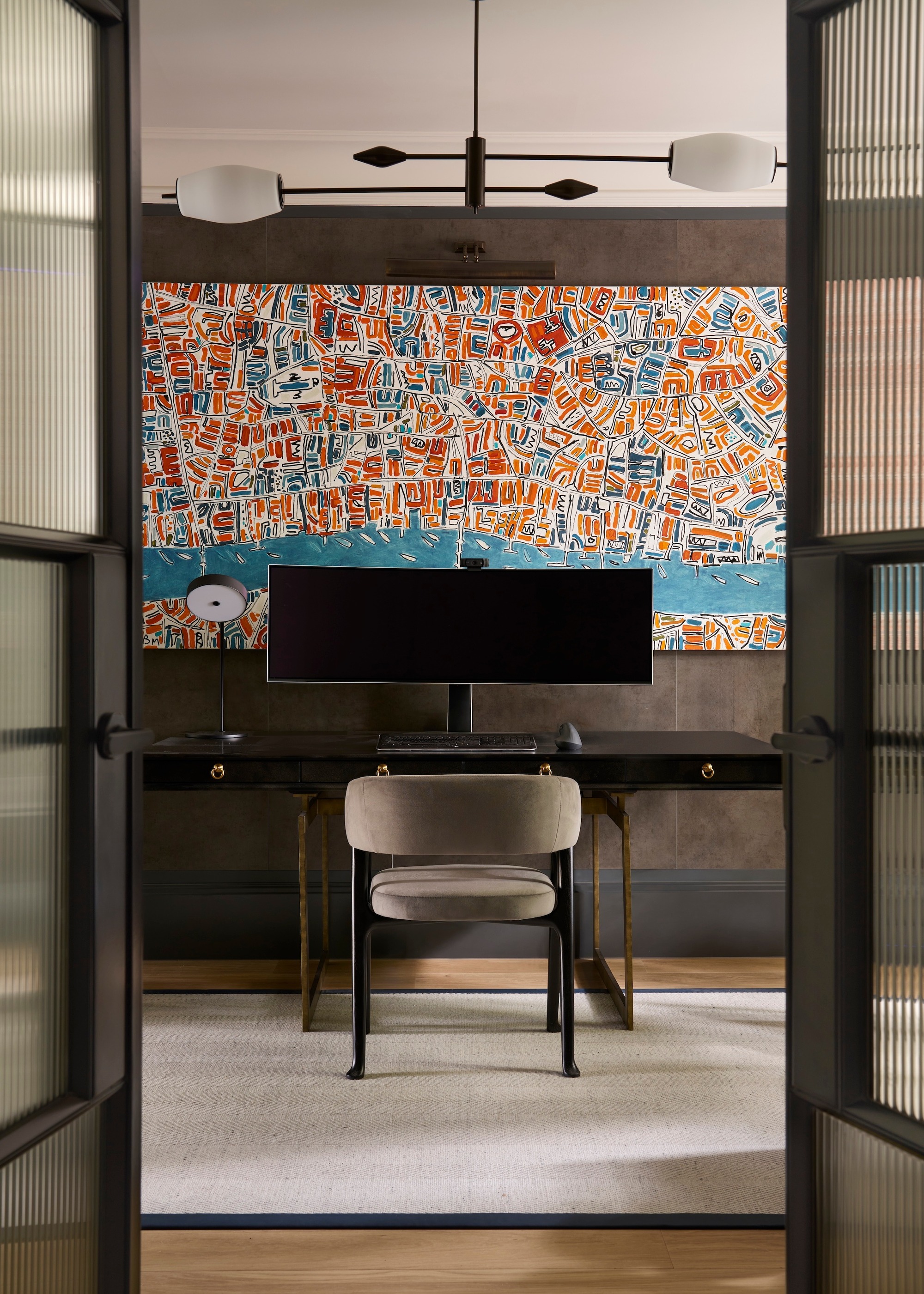 A home office with patterned wallpaper and glass doors
