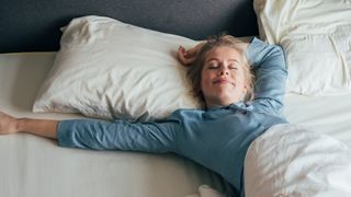 Woman wakes up in bed smiling