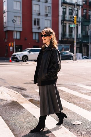 Halie LeSavage wearing a leather bomber jacket, a midi skirt, black boots,