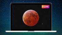 graphic showing a blood moon during a total lunar eclipse in the center of a laptop screen with a pink and yellow "live" sign in the top right corner.