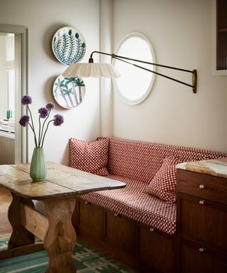 upholstered banquette coffee nook seat with antique wooden table and wall light on an arm