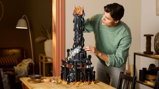 Lego Barad-dûr being built on a table, by a man in a green jumper